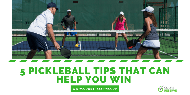 Four people playing pickleball on an outdoor court.