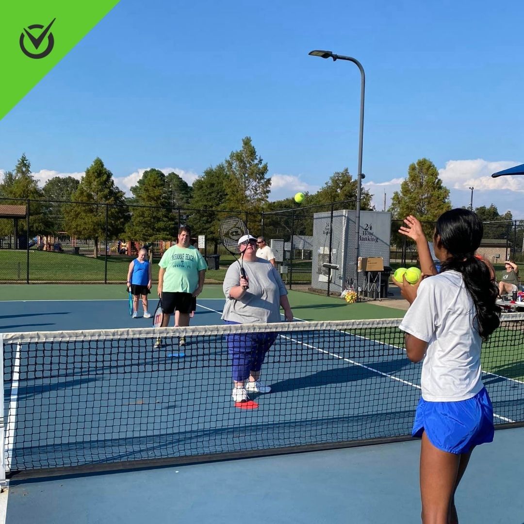 Photo of Northeast Arkansas Tennis players toss and hit tennis balls to each other
