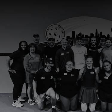 pickleball-charlotte-courtreserve Group of people smiling in front of pickleball sign