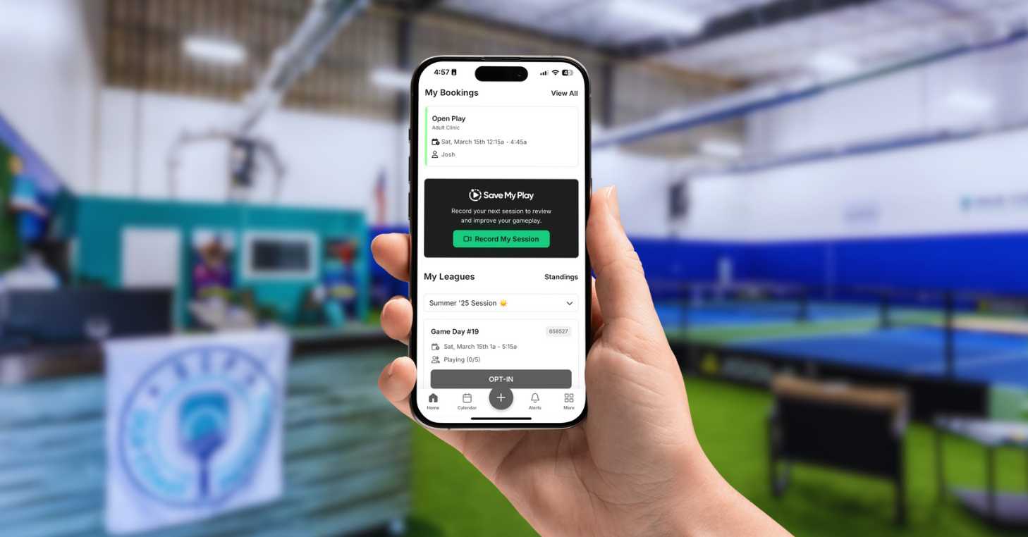 Old Coast Pickleball interior in background. In foreground, a hand holds an iPhone displaying the CourtReserve mobile app with the new Save My Play feature.