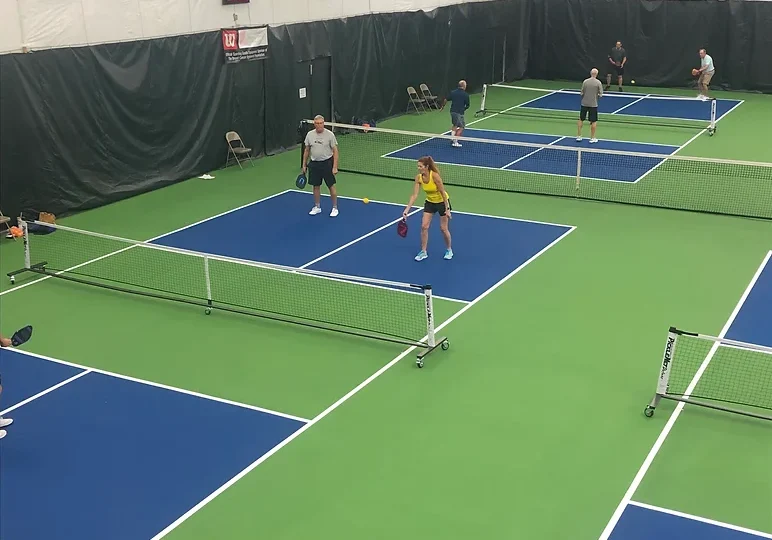 Indoor pickleball courts with several people playing matches.